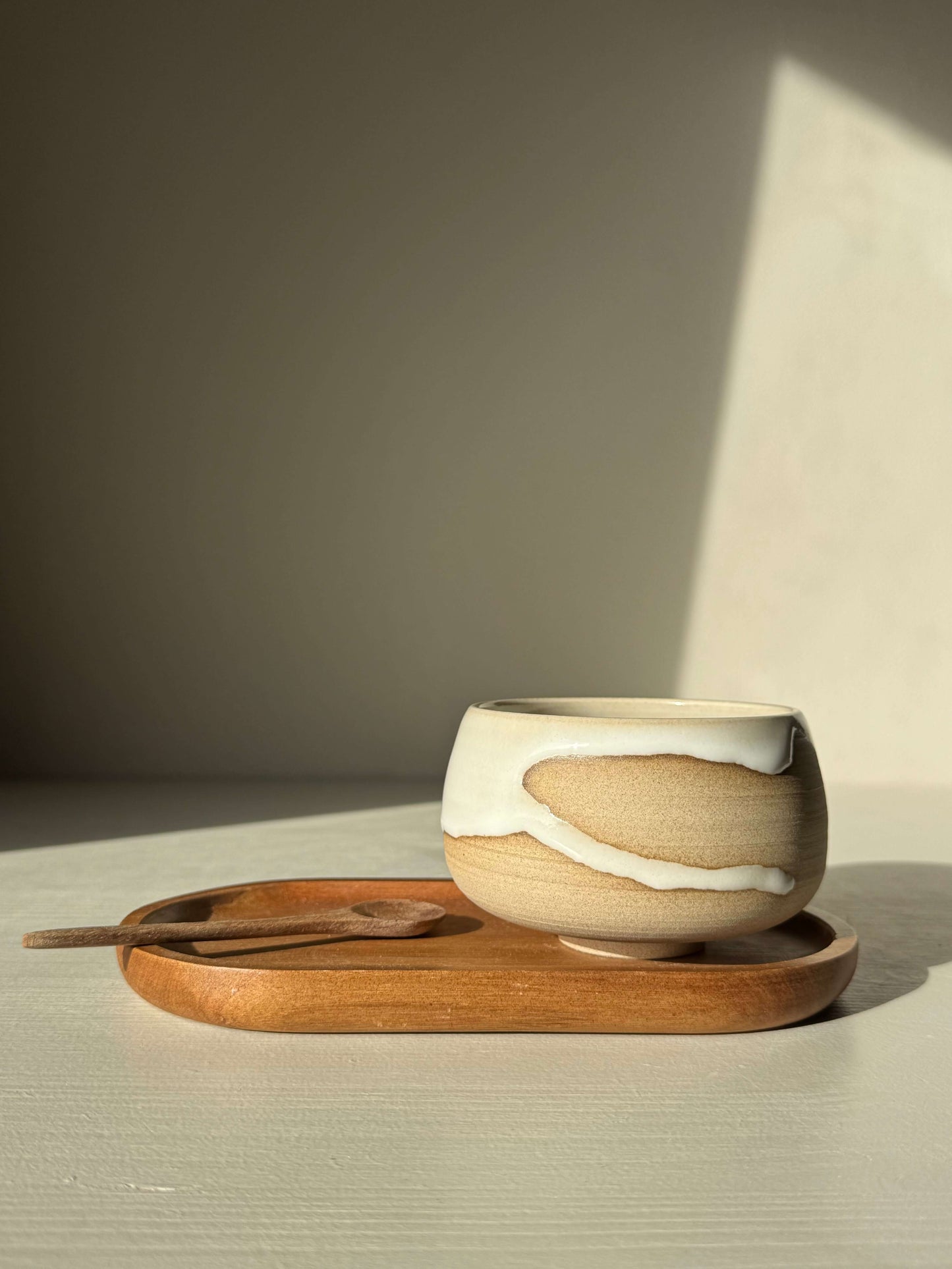 Yuki handmade ceramic coffee cup with toffee clay and white glaze on wooden tray