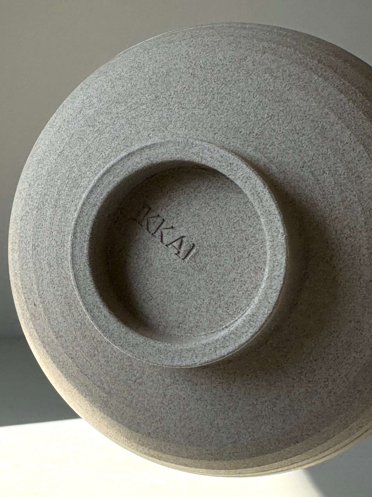 Bottom of Yuki Series Matcha Bowl showing 'IKKAI' engraving on toffee clay texture.