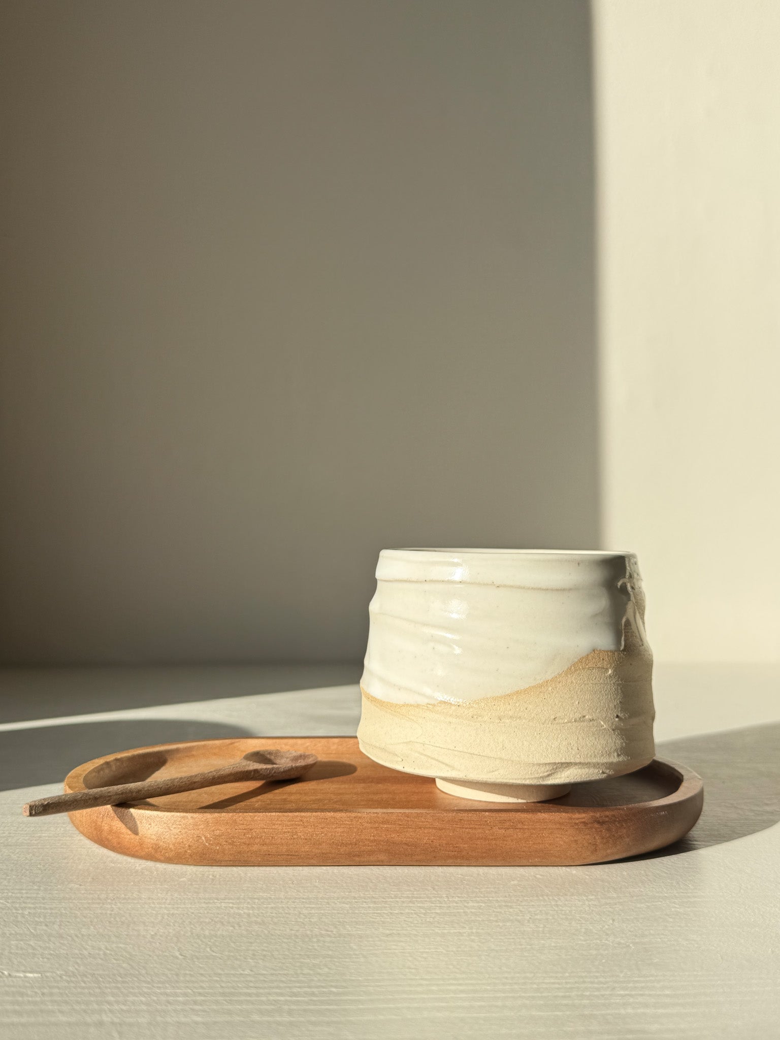 Yunomi Cup – Glossy White #01 on a wooden tray with spoon, perfect for warm beverages, showcasing elegant soft curves and a natural glaze.
