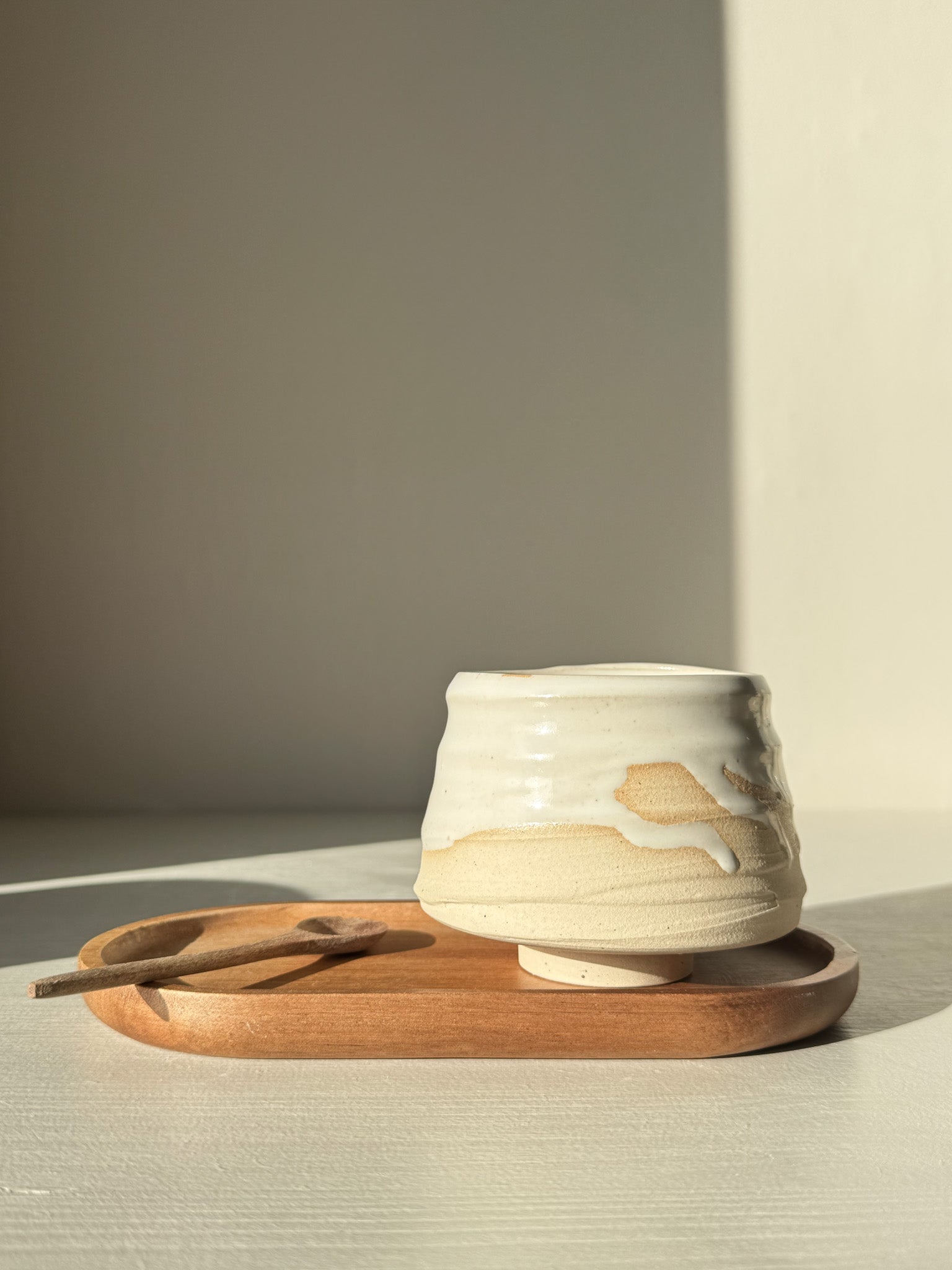 Yunomi Cup – Glossy White #02 on wooden tray, showcasing soft curves and glossy white glaze, perfect for tea or coffee.