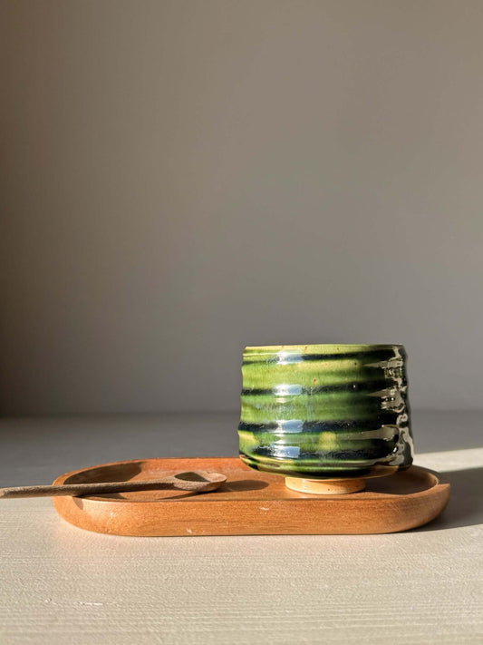 Yunomi Cup - Hinoki #10 with deep green glaze and hand-applied slip design on display with wooden tray and spoon.