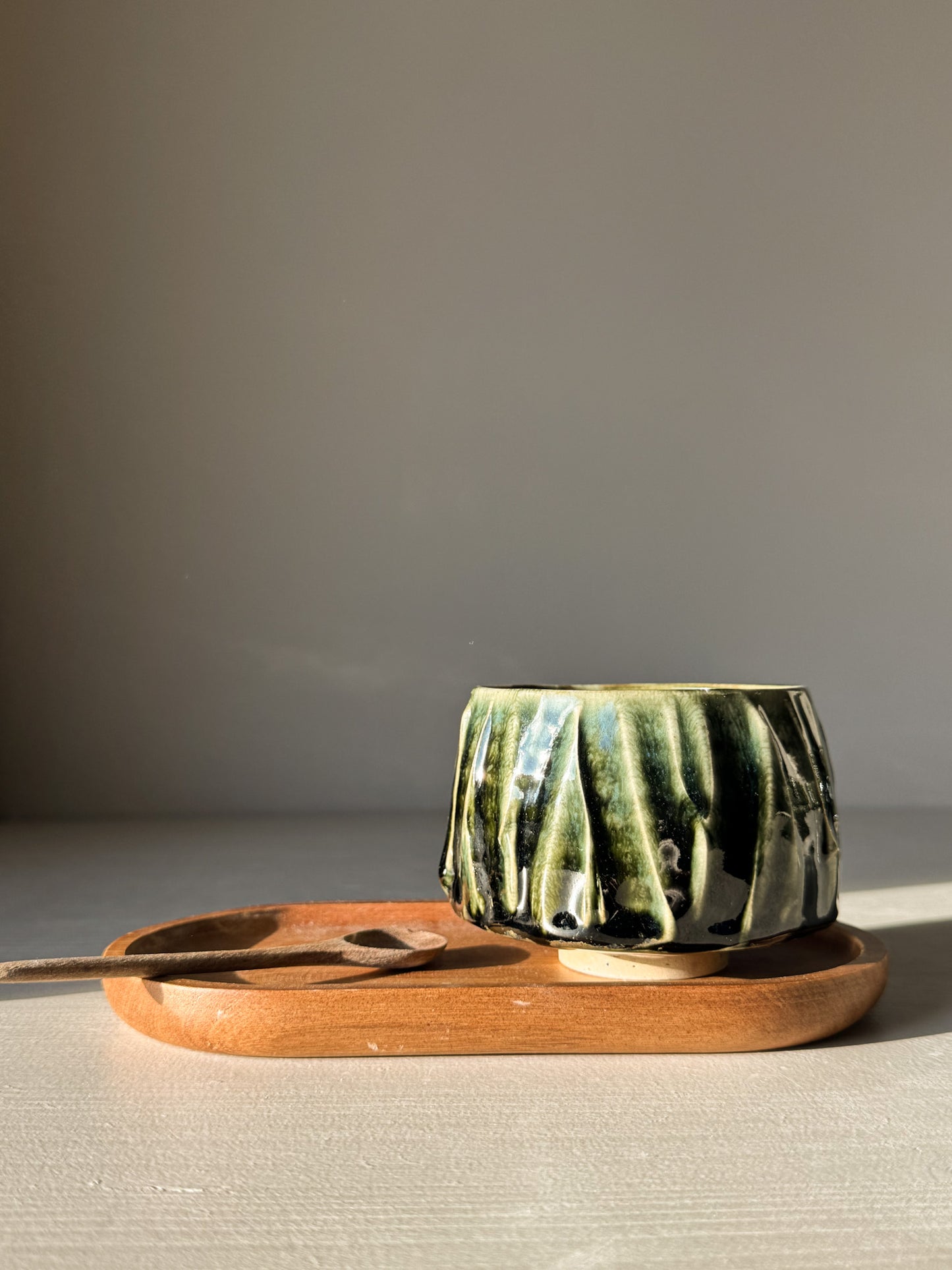 Yunomi Cup - Hinoki #11 with deep green glaze on wooden tray, showcasing handcrafted texture and unique design.