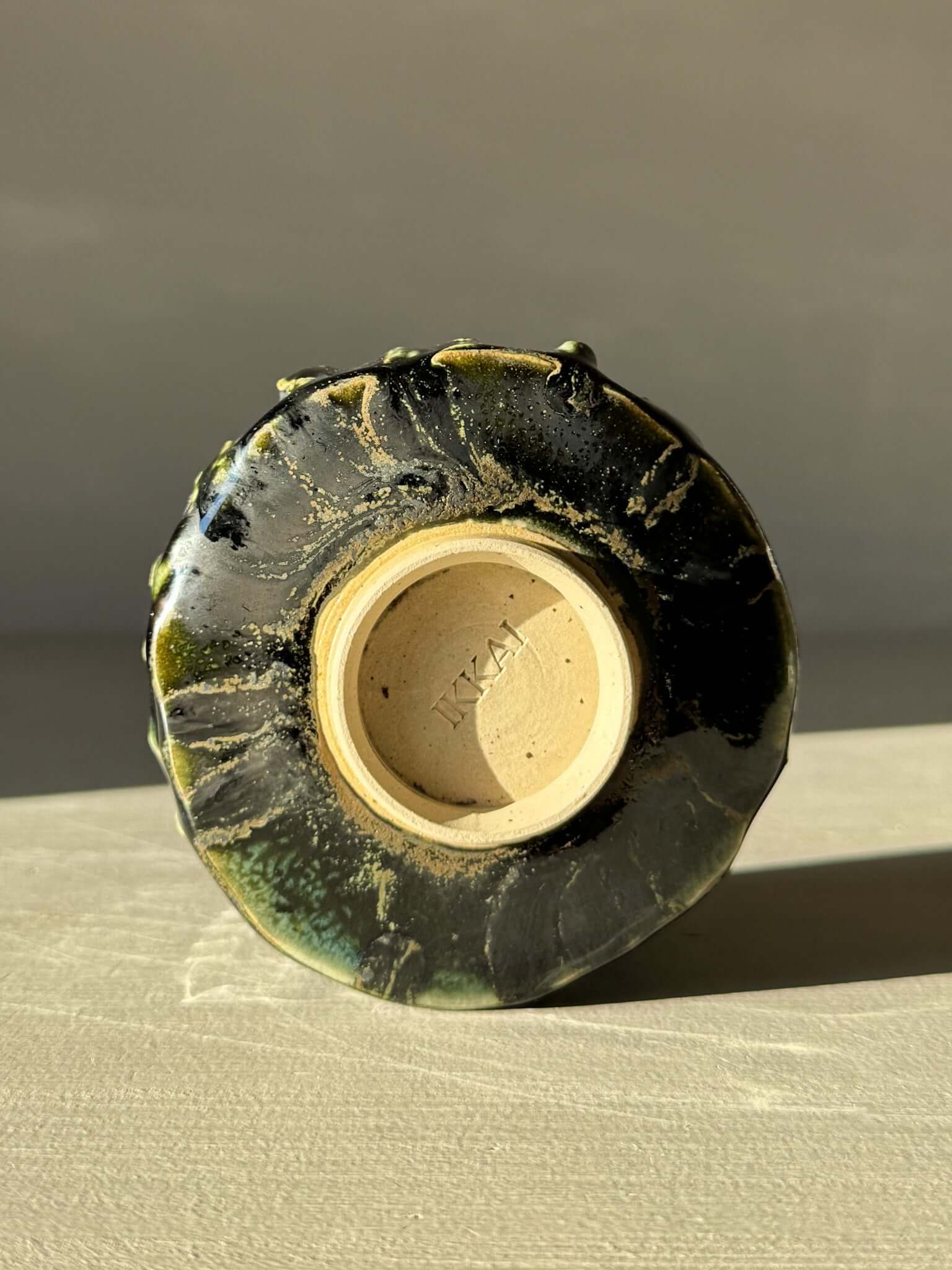 Bottom view of Yunomi Cup - Hinoki #11 showcasing hand-decorated slip texture and deep green glaze detail.