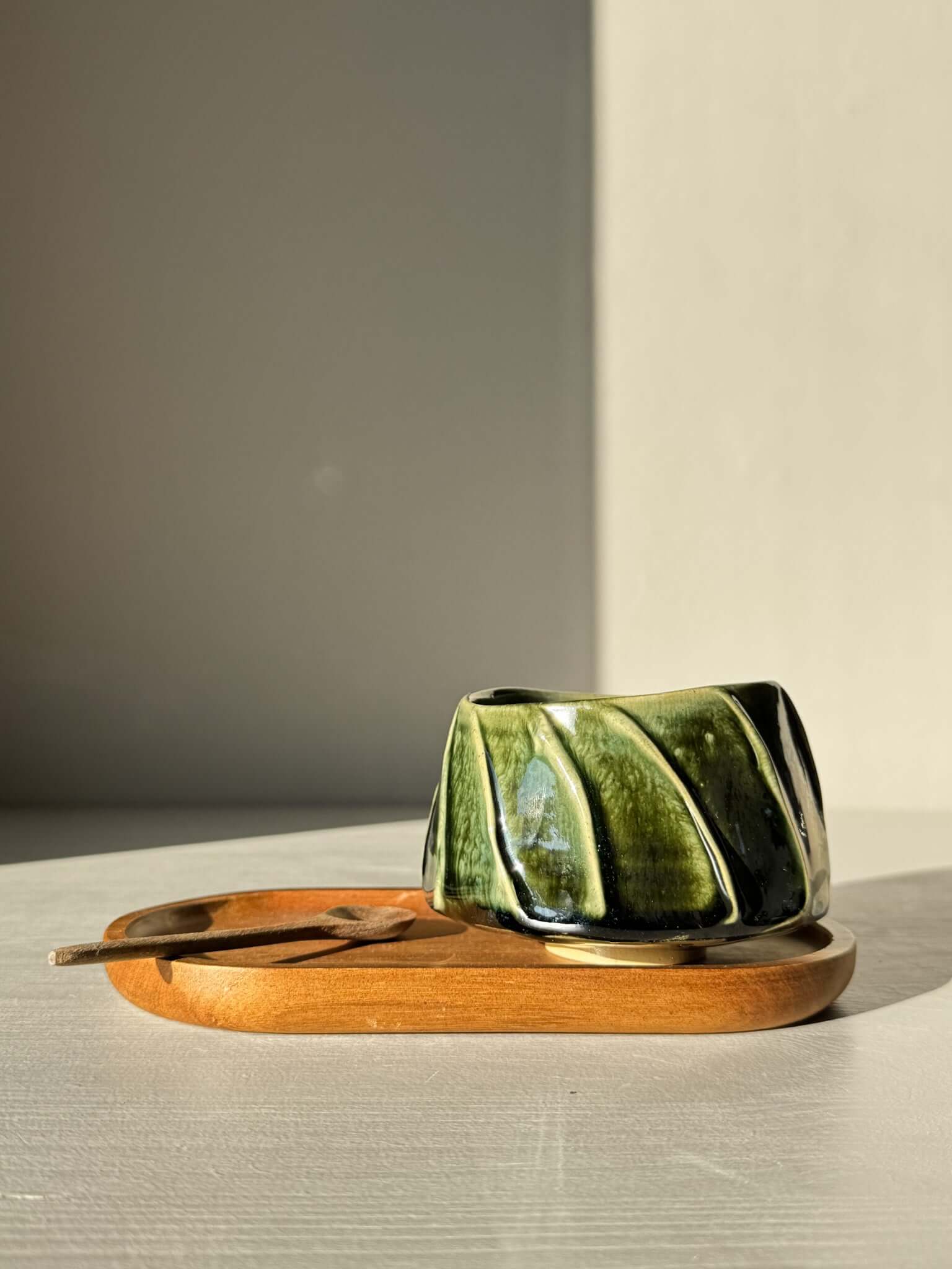 Yunomi Cup - Hinoki #27 in deep green glaze, featuring hand-applied slip decoration with flowing lines, on a wooden saucer.