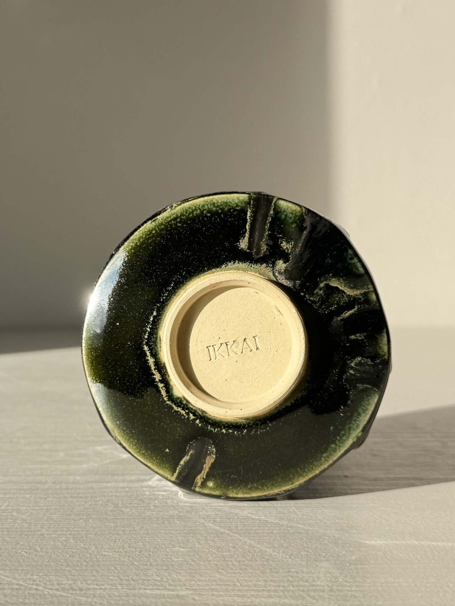 Bottom view of Yunomi Cup - Hinoki #29, showing handmade slip design and deep green glaze.