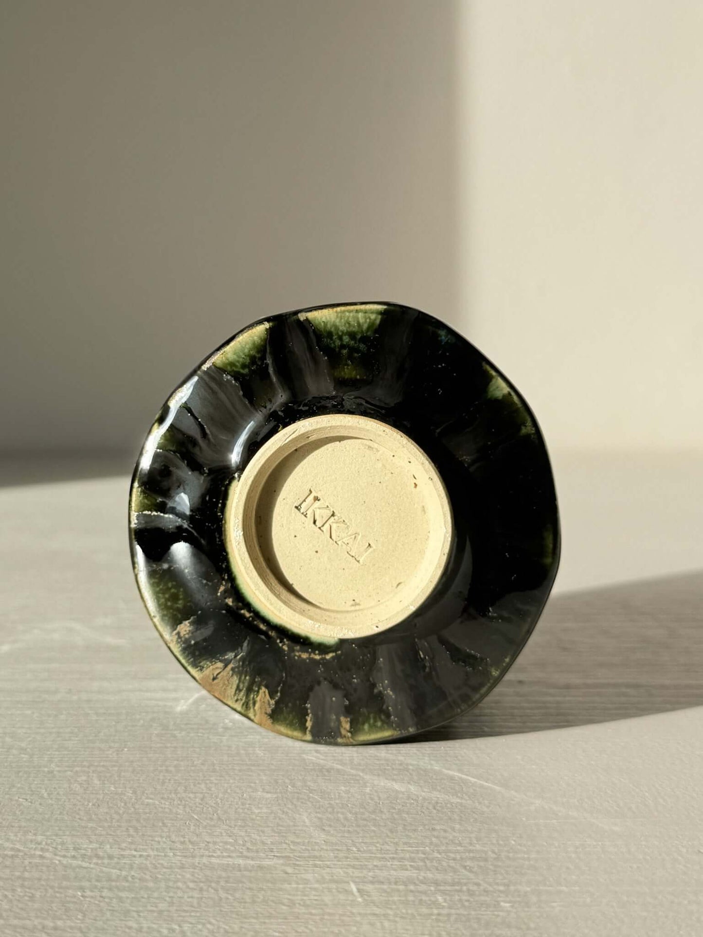 Base of hand-crafted Yunomi Cup - Hinoki Series #24 with deep green glaze highlights and unique slip texture.