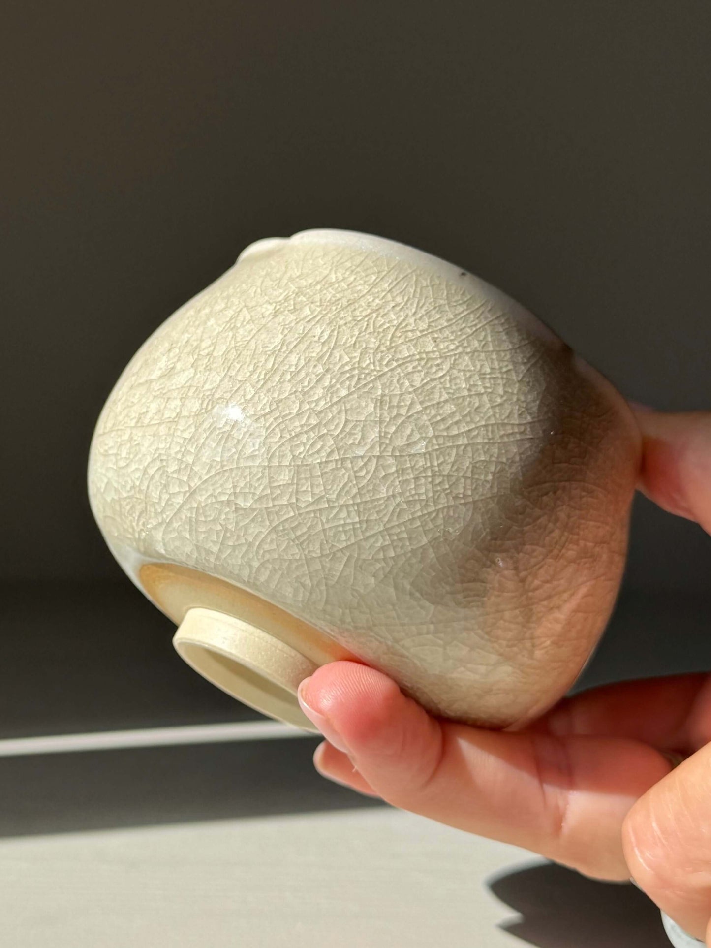 Hand holding a Yunomi Cup - Kannyū Series #05, a handmade ceramic with crackle glaze and flowing rim.