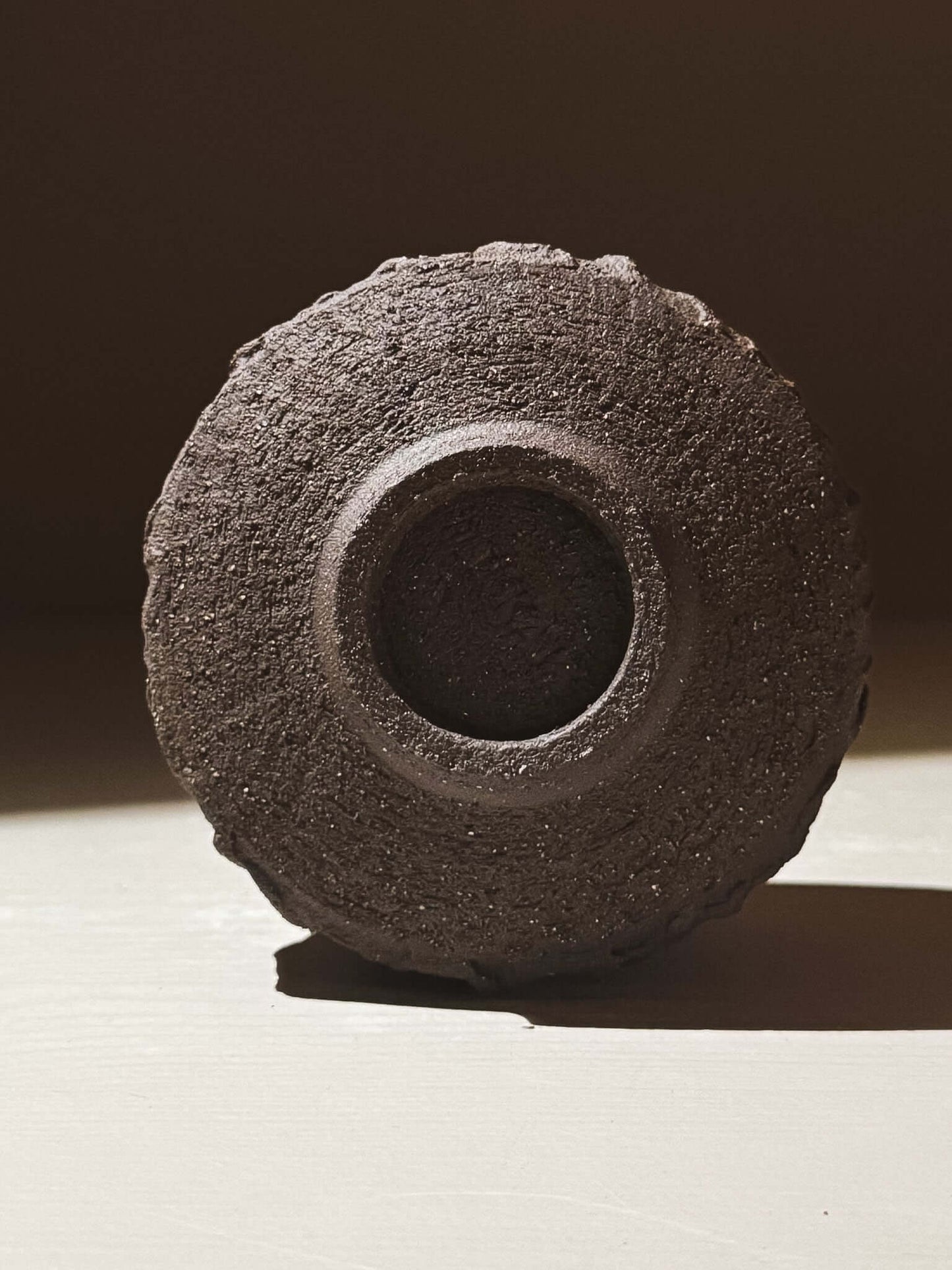 Bottom view of Yunomi Cup - Kuro #01 showcasing textured dark brown clay and earthy design.