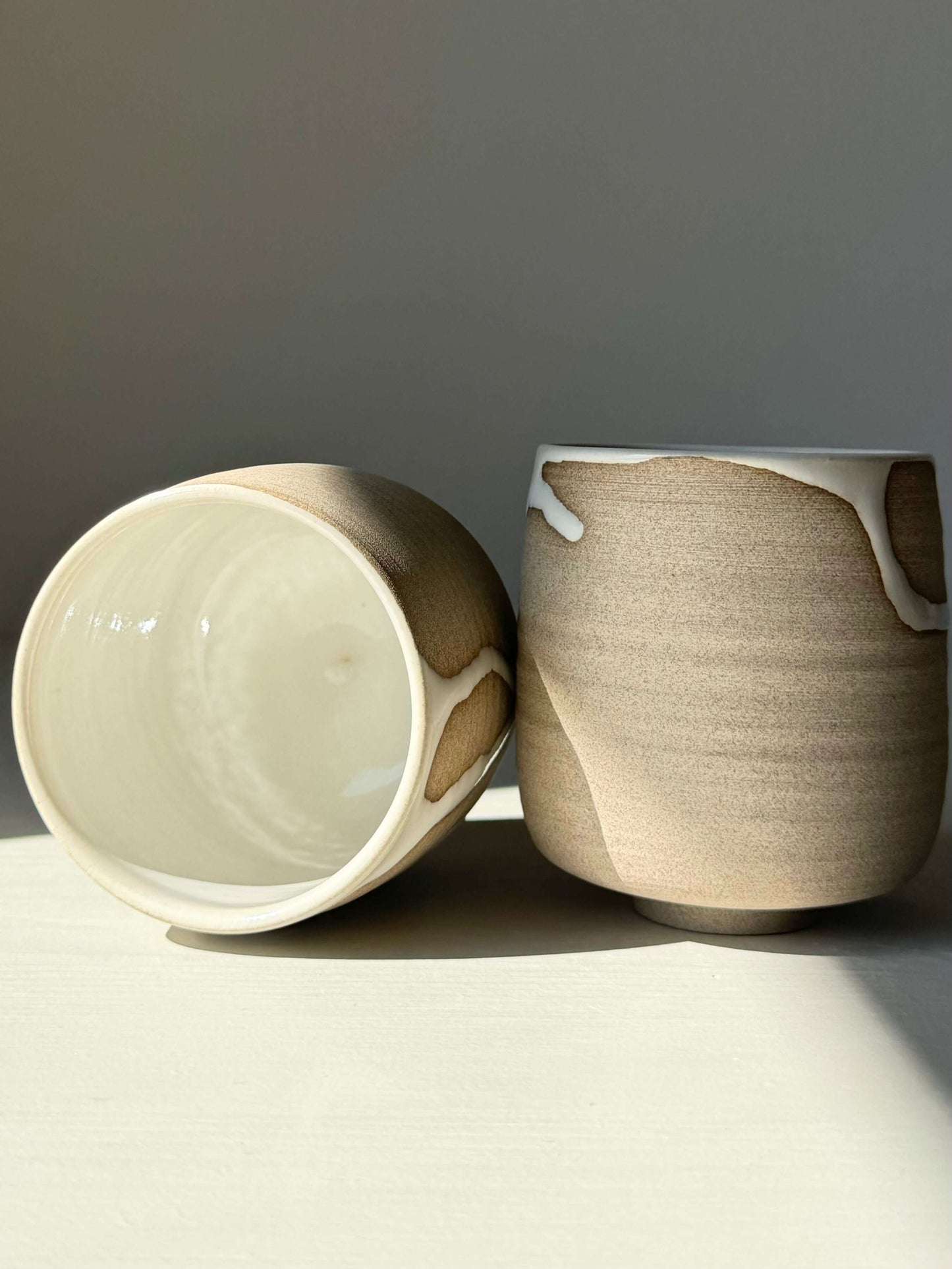 Yunomi Cups from Yuki Series with white glaze on toffee clay, showcasing unique drips and texture, in natural light.