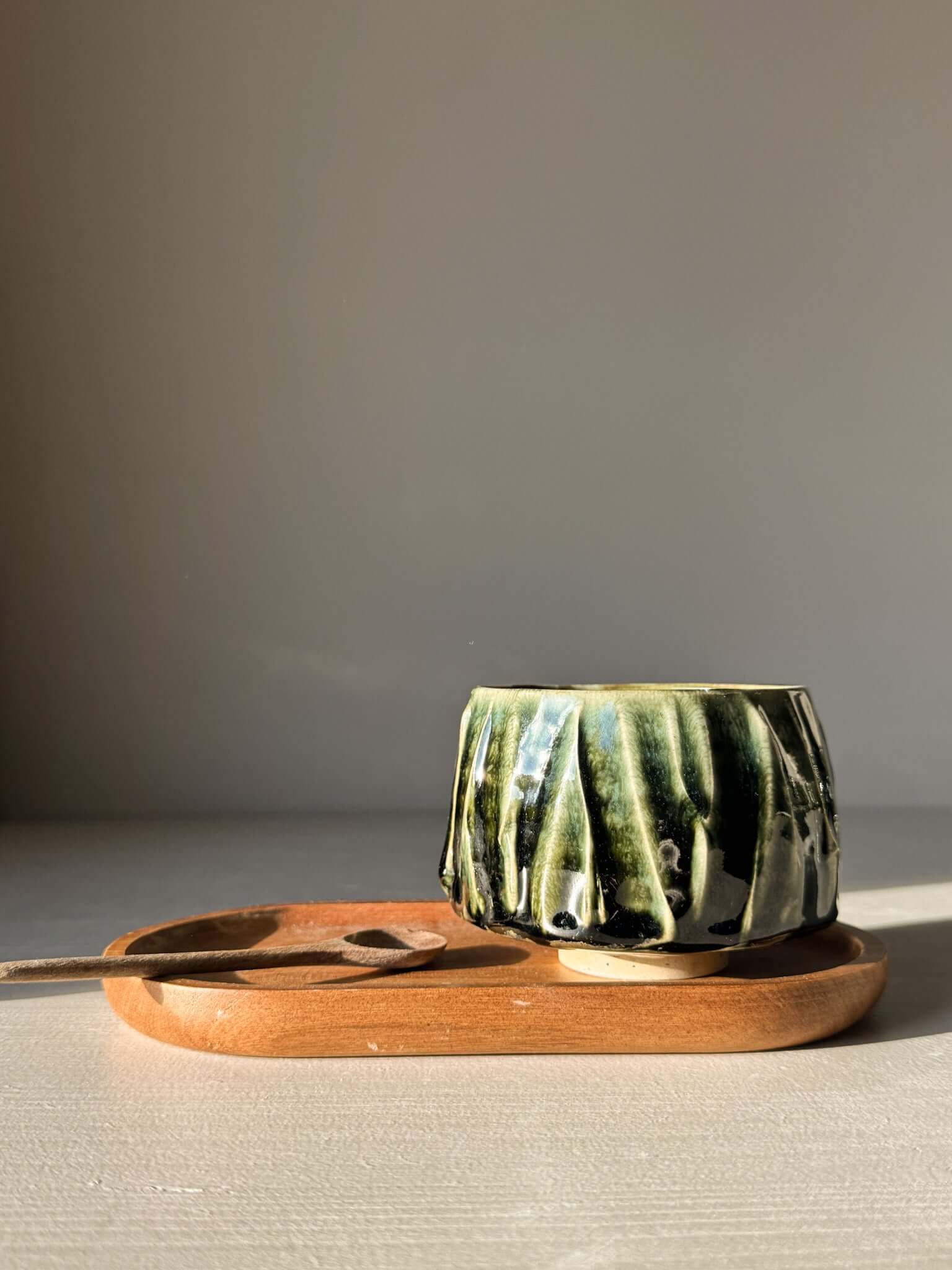 Yunomi Cup - Hinoki #11 with deep green glaze on wooden tray, showcasing handcrafted texture and unique design.