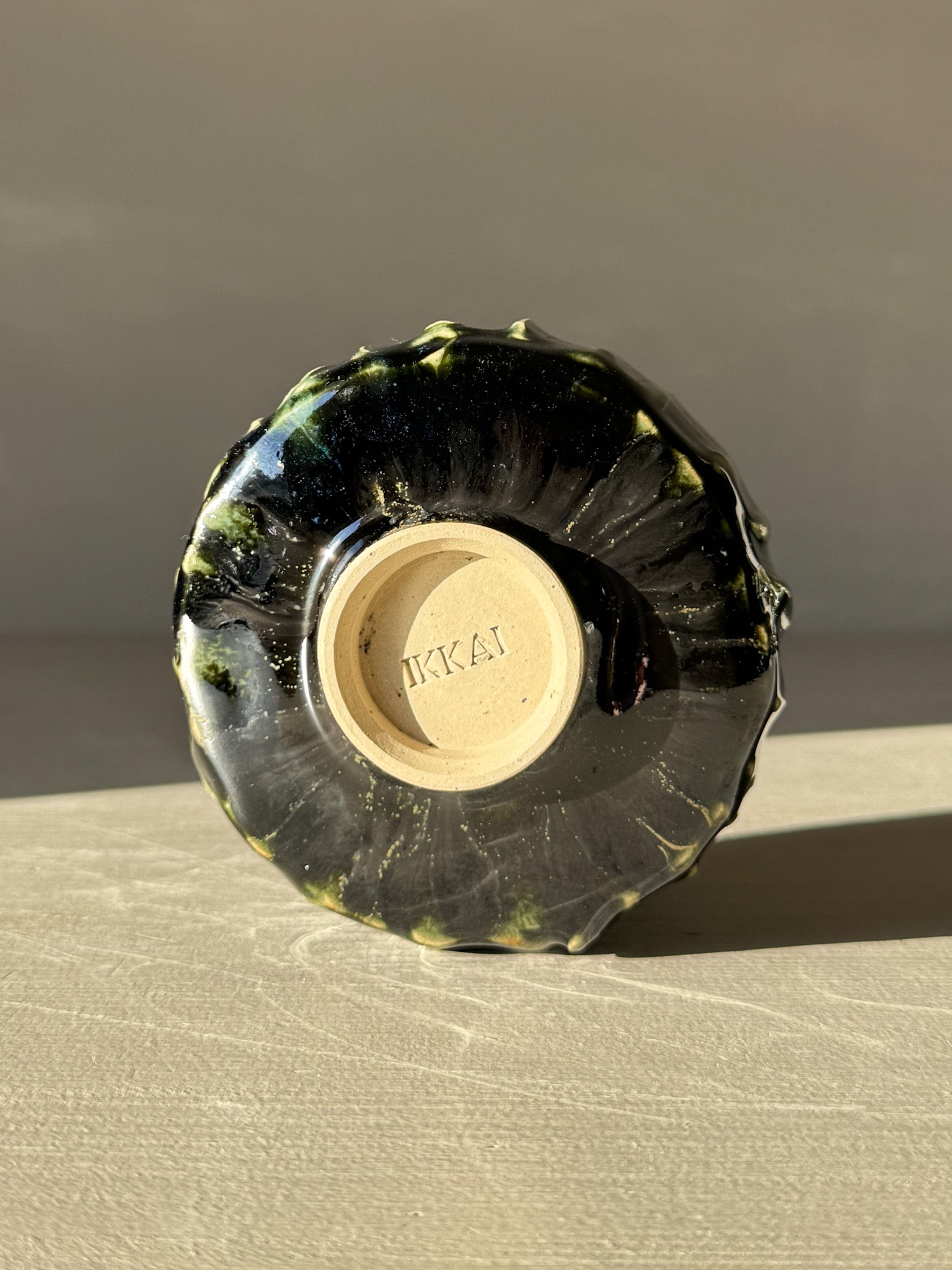 Bottom view of handmade Yunomi Cup - Hinoki #12 with deep green glaze and slip texture.