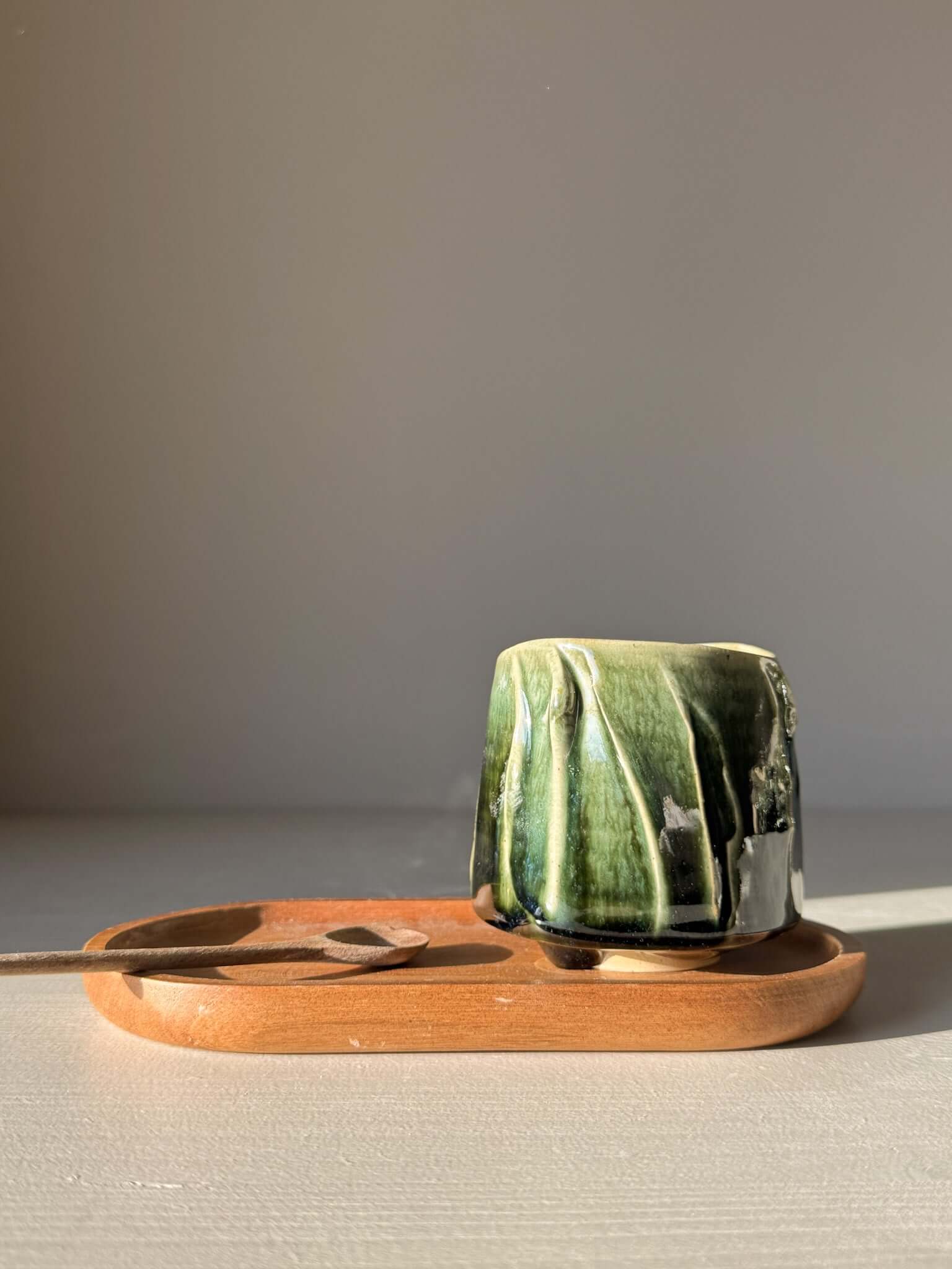 Handcrafted Yunomi Cup - Hinoki #14 with deep green glaze on a wooden tray, showcasing the unique texture and design for tea moments.