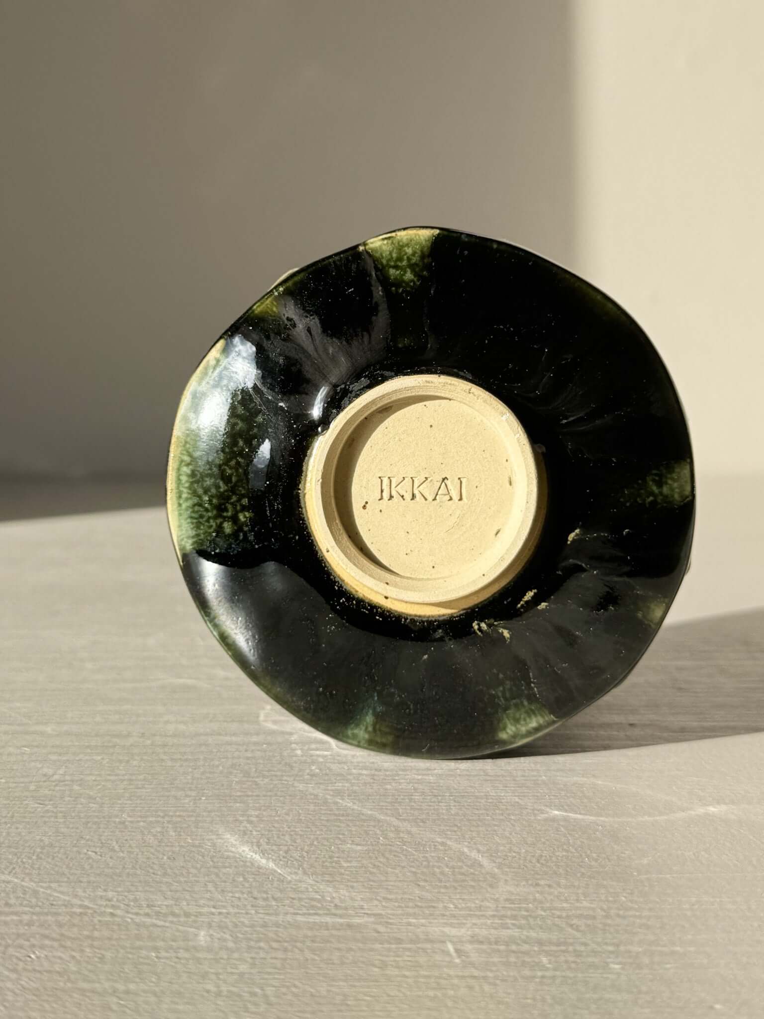 Bottom view of Yunomi Cup - Hinoki #26 showing deep green glaze with handmade texture by IKKAI.
